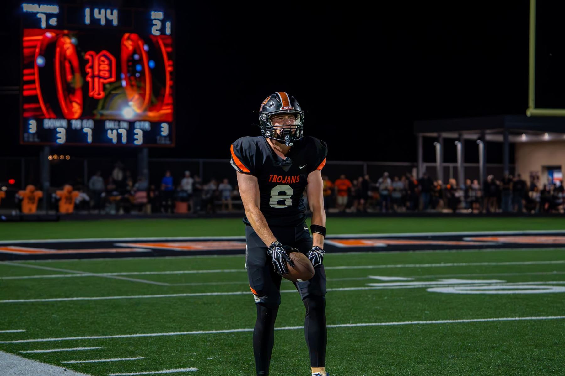 Pleasantville football player standing under the stadium scoreboard at night